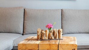 A wooden coffee table with a vase of flowers, placed on a gray sofa. - Apartment 'Romantische Whg In Ruhiger Lage' with Private Garden and Wi-Fi (Stelle)