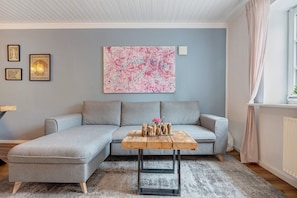 A modern living room with a grey sectional sofa, a wooden coffee table, and a large abstract painting on the wall.