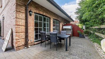 A brick house with a patio, outdoor seating, and a barbecue grill.