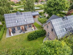 Un immeuble résidentiel doté de panneaux solaires sur le toit, d’une allée pavée et d ’une pelouse bien entretenue.
