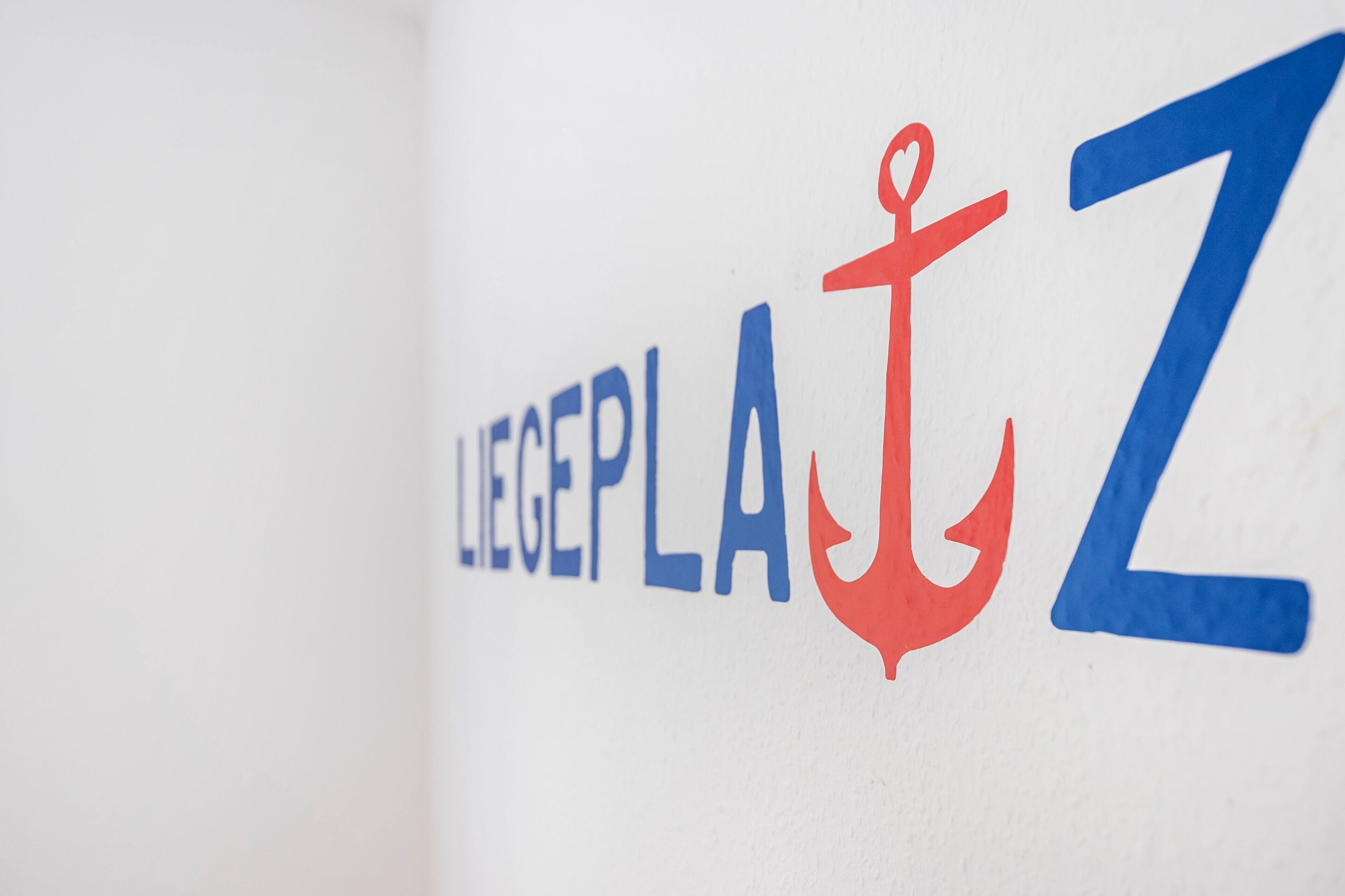 Ein Logo mit dem Text 'LIEGEPLA' und einem Ankersymbol.