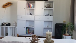 A white cabinet with multiple shelves, drawers, and a small ship model.