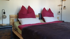 A bed with two pillows, a bedside table, a lamp, and a wall-mounted light fixture.