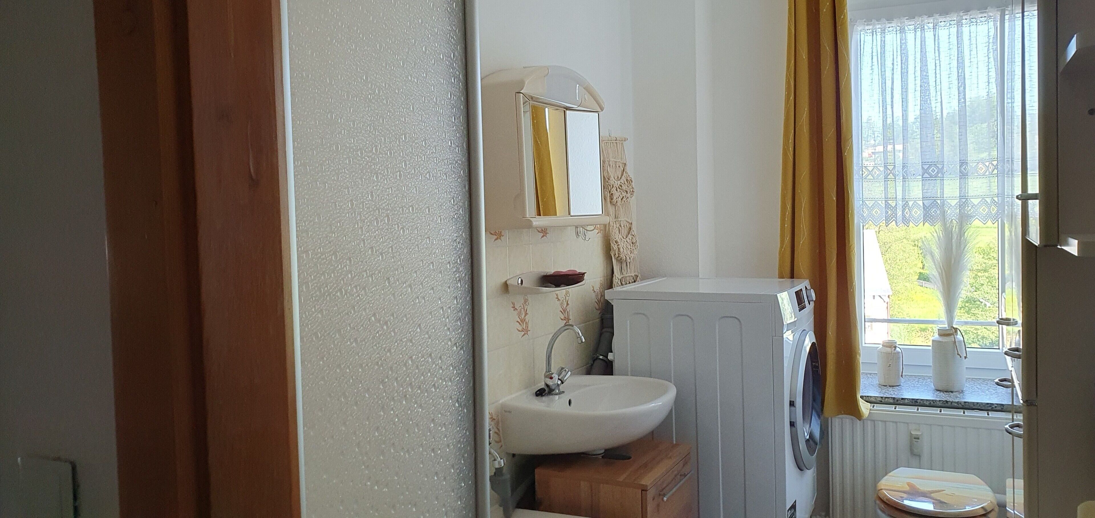 A bathroom with a sink, mirror, and washing machine.