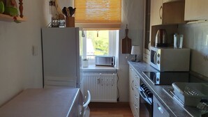A compact kitchen with a refrigerator, microwave, and stove.