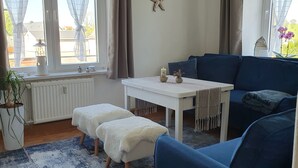 A cozy room with a white table, blue sofa, and a potted plant.