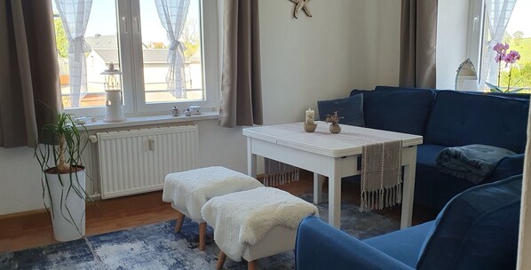 A cozy room with a white table, blue sofa, and a potted plant.