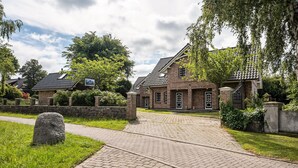 A brick building with a paved driveway and a stone pathway leading to the entrance.