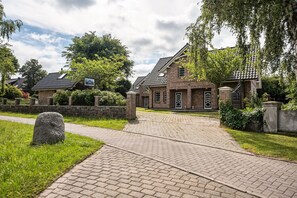 Un bâtiment en briques avec une allée pavée et un chemin de pierre menant à l’entrée.