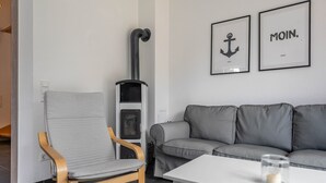 A modern living room with a grey sofa, a wooden chair, a white table, and a fireplace.