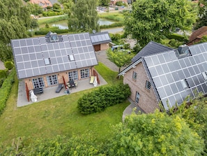 A residential building with solar panels on the roof, a paved driveway, and a well-maintained lawn.
