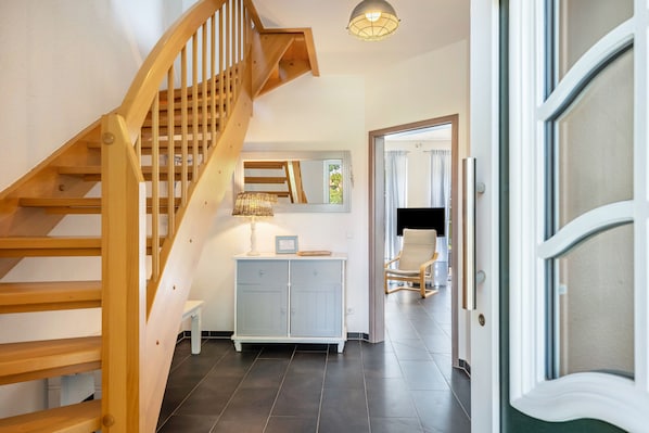 A wooden staircase leading to a room with a mirror, a cabinet, and a chair.