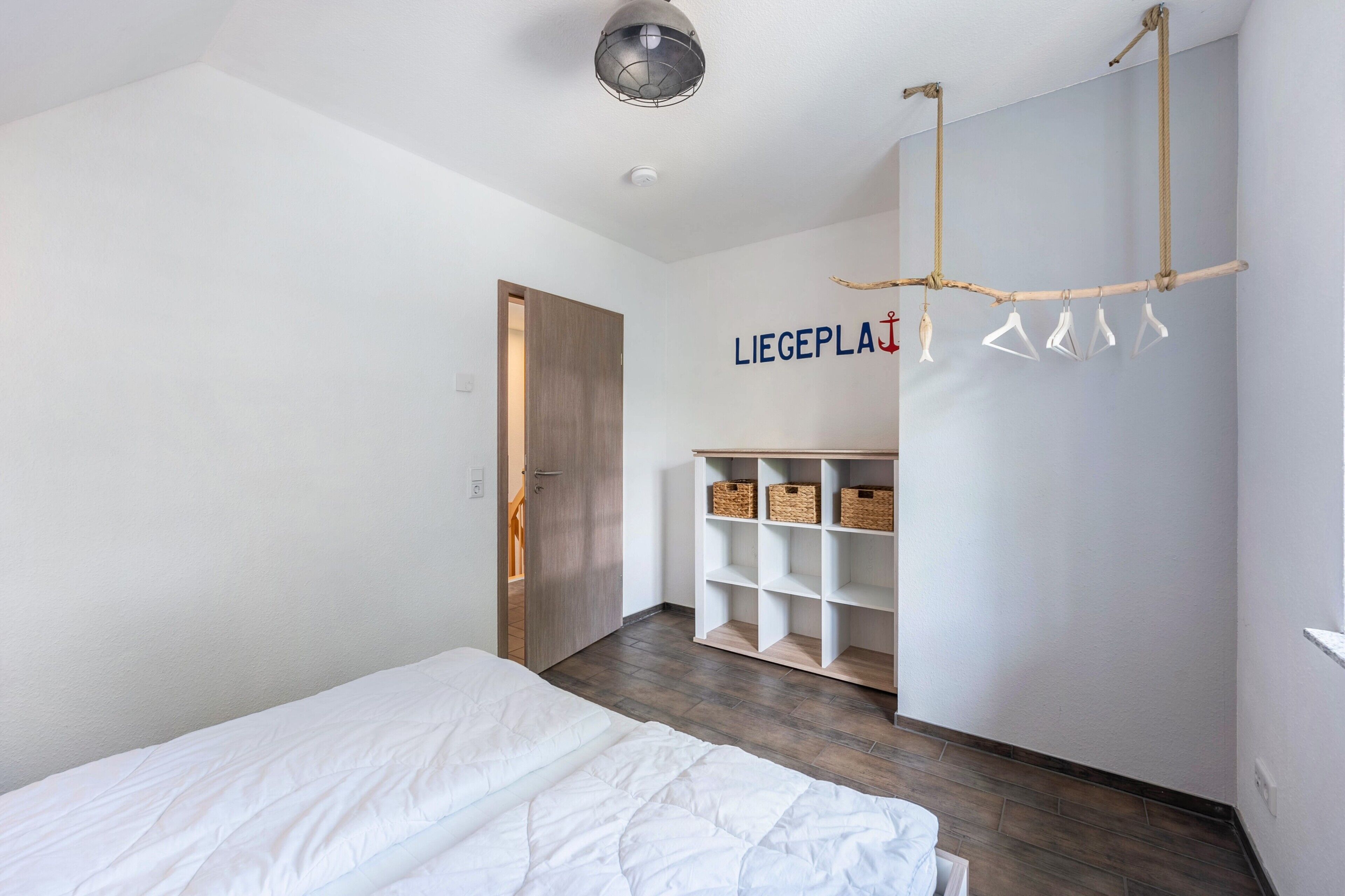 Ein Schlafzimmer mit Bett, Kleiderschrank und Kleiderstange mit Kleidung.