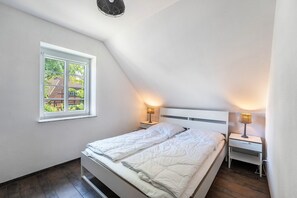 A bedroom with a bed, two bedside tables, a window, and a ceiling light fixture.