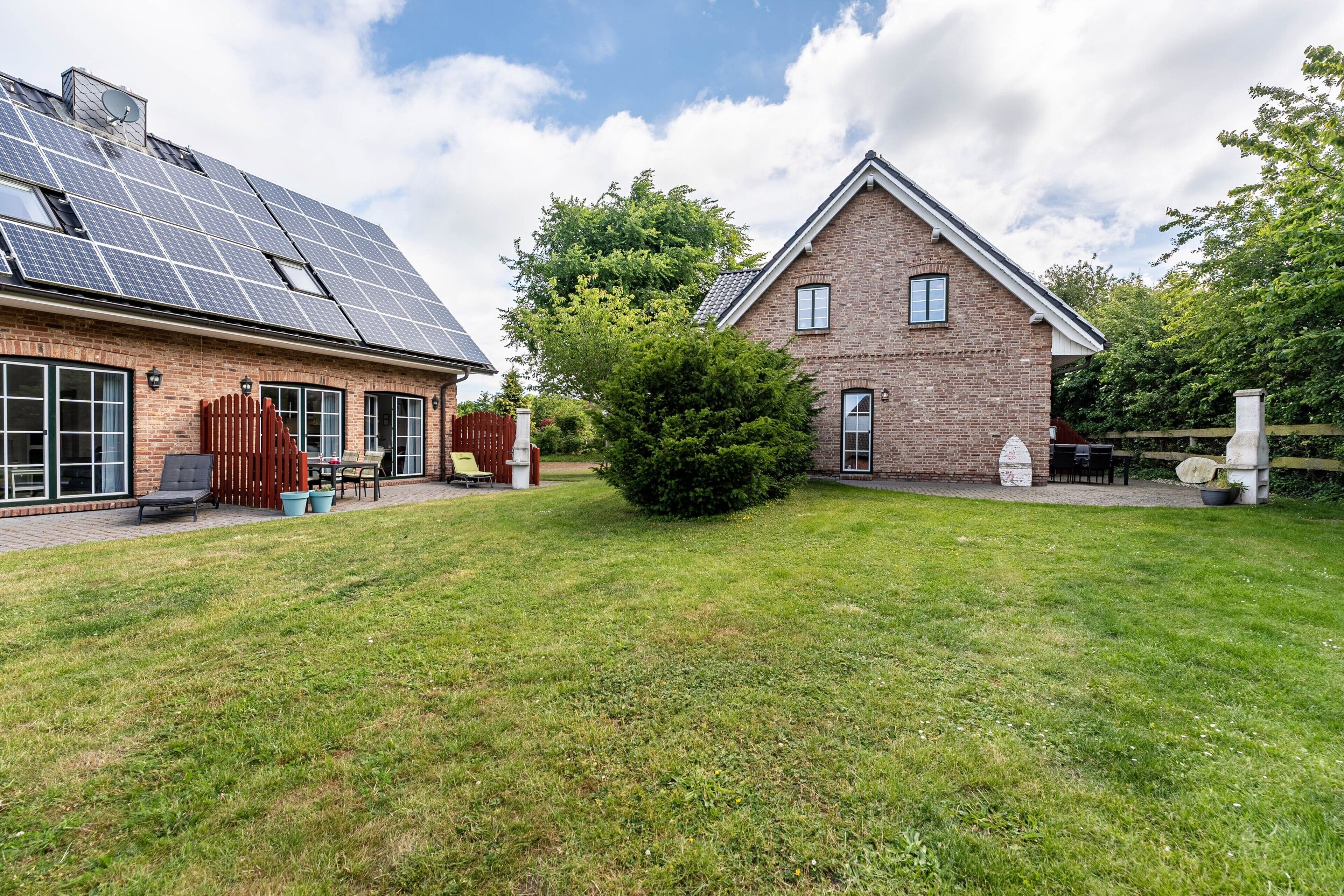 A house with solar panels, a brick exterior, and a well-maintained lawn.