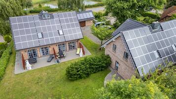 Un immeuble résidentiel doté de panneaux solaires sur le toit, d’une allée pavée et d’une pelouse bien entretenue.