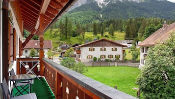 Ein Balkon mit Bergblick, einer Holzzaun und einem Gebäude mit weißer Fassade.