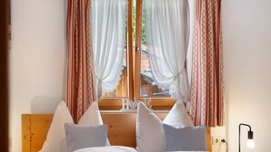 Een tweepersoonsbed met witte beddengoed, een houten hoofdbord en twee kussens.