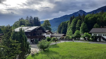 A rural village with traditional wooden houses, a paved road, and mountains in the background.