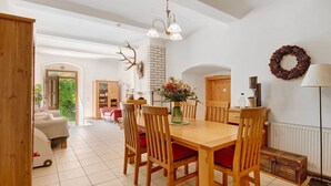 Comedor con mesa y sillas de madera, un jarrón de flores y una chimenea.
