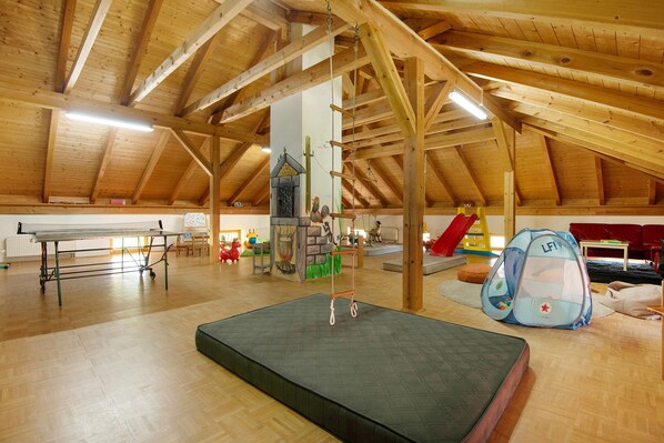 An indoor play area with a trampoline, playpen, and climbing structure.