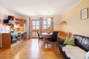 A kitchen with wooden cabinets, a dining table with chairs, a sofa, and a view through a door.