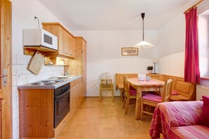 A compact kitchen with wooden cabinets, a microwave, and a dining area with a table and chairs.
