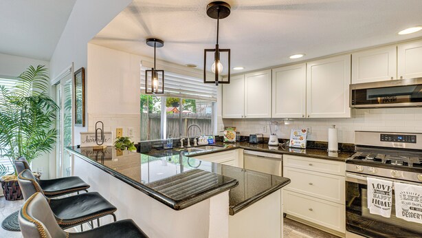 A modern kitchen with white cabinets, a central island, and a built-in oven. - Pet-Friendly Spring Home w/ Private Pool & Hot Tub (Spring)