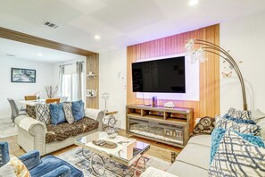 A modern living room with a large flat-screen TV, comfortable sofas, a coffee table, and a decorative fish tank. - Welcoming Home ~ 16 Mi to Downtown Houston! (Houston)