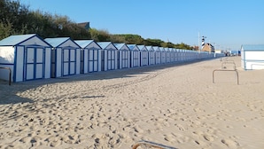 A row of beach huts with a sandy beach in the foreground.
