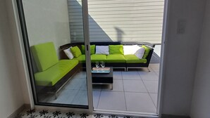 A balcony with a green sofa and a small table, both with cushions.