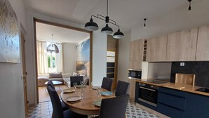A modern kitchen with a dining area. It includes a wooden dining table with chairs, a kitchen counter, and a microwave.