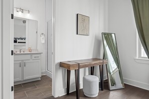 Bathroom features a white vanity, wooden bench, and large mirror.