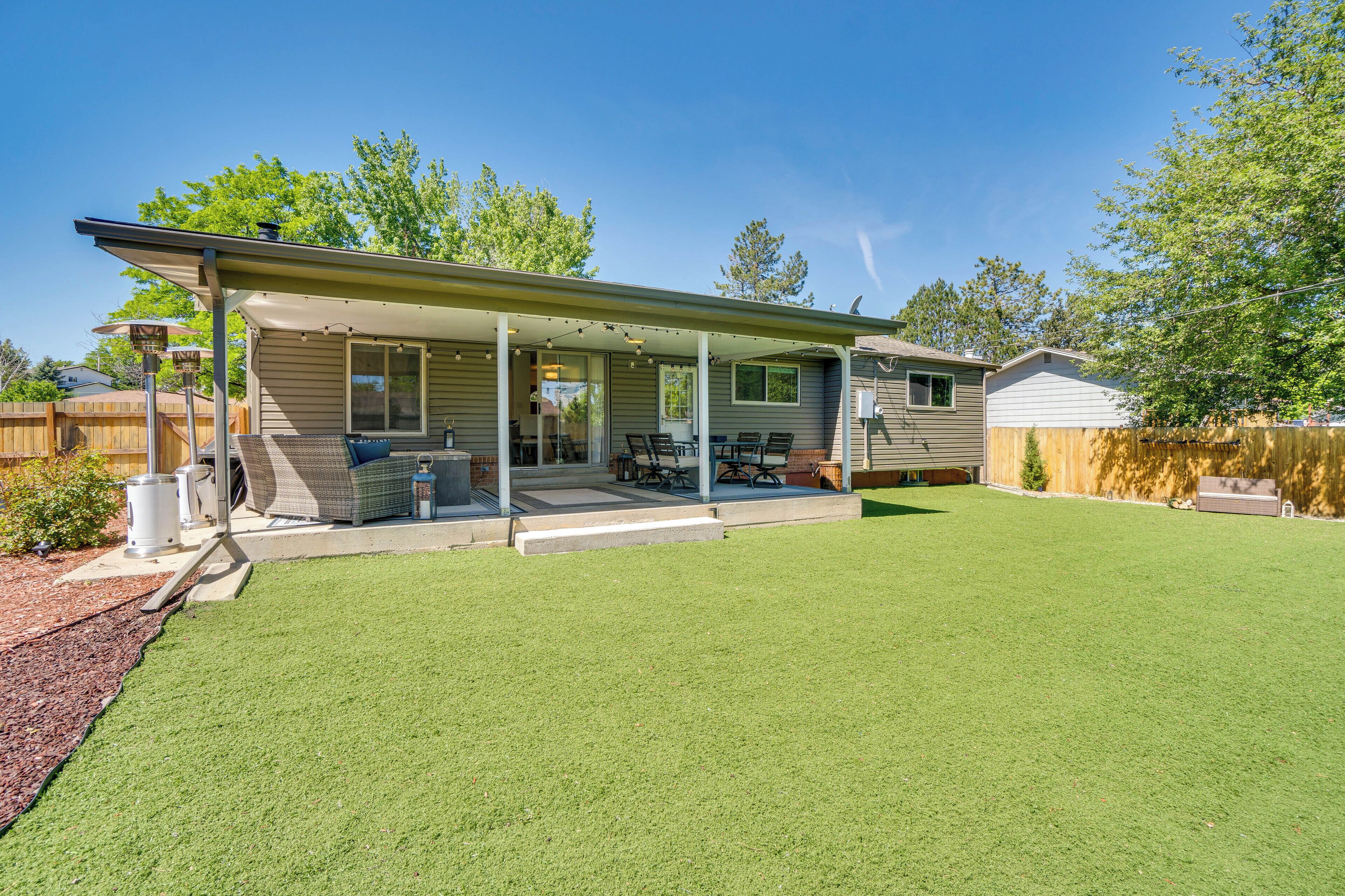 A single-story house with a covered patio, a lawn, and a wooden fence.