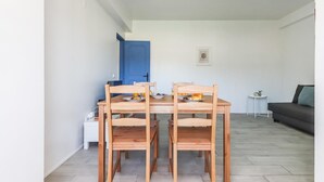 Un comedor con una mesa y sillas de madera, una puerta azul, una mesita auxiliar blanca y un sofá gris en un espacio de estar moderno.