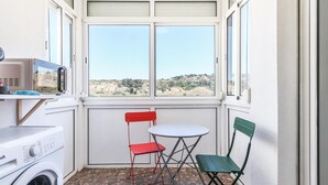 Una cocina compacta con lavadora, microondas y vistas a un paisaje montañoso a través de amplios ventanales.