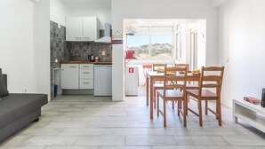 Una cocina moderna con armarios blancos, salpicadero de azulejos y una zona de comedor con sillas y mesa de madera.