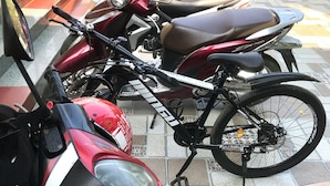 A red and black motorcycle parked on a tiled patio with a garden in the background. - Happy field homesaty (Phong Nha)