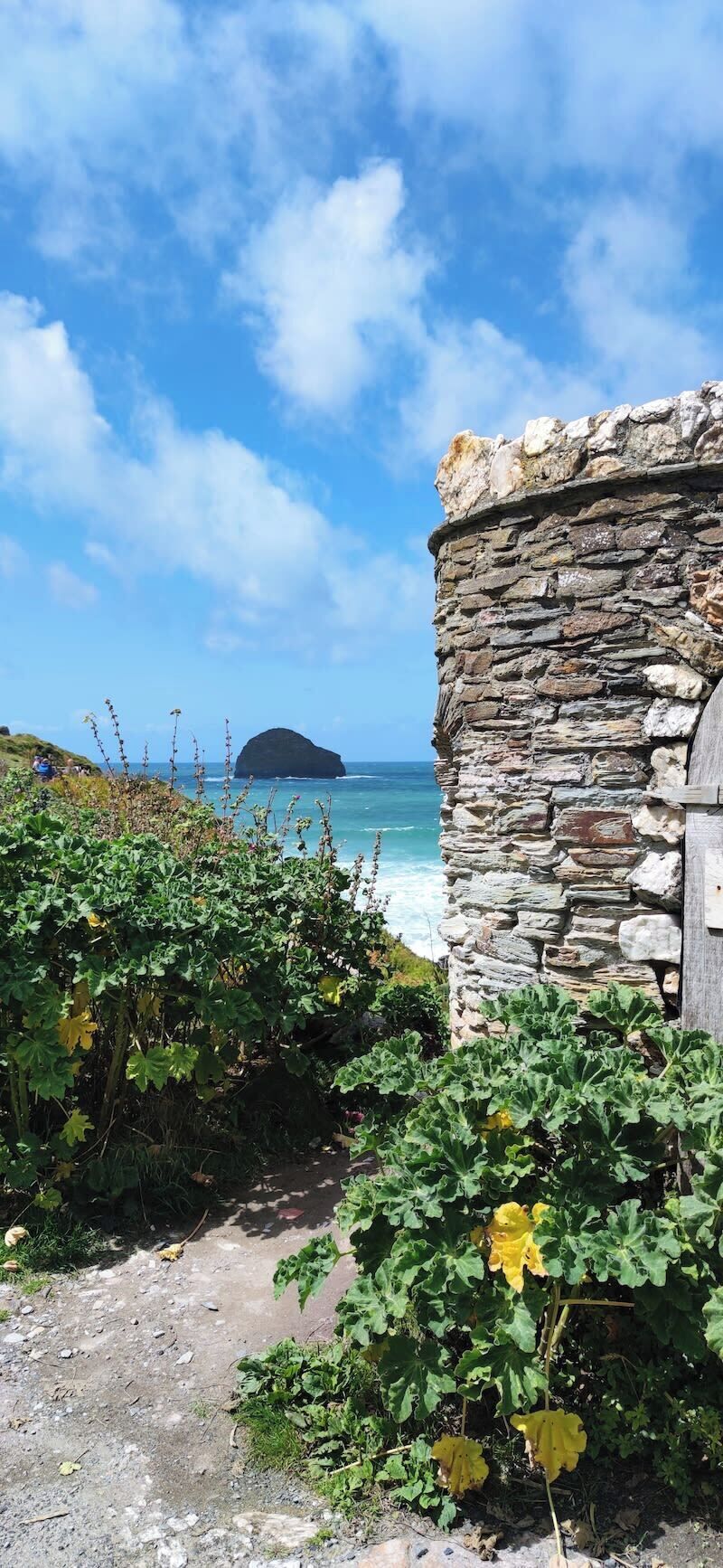 A stone building with a view of the sea and a small island in the distance.