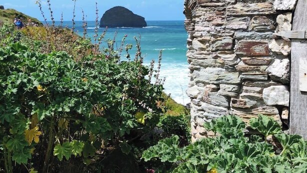 Un bâtiment en pierre offrant une vue sur la mer et une petite île au loin.