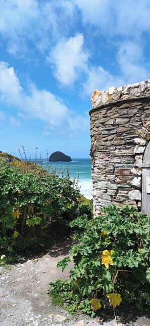 Un edificio de piedra con vistas al mar y una pequeña isla en la distancia.