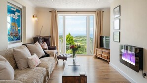 Un salon avec un canapé, une table basse, un téléviseur et une vue sur la campagne.