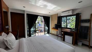 A hotel room with a bed, a desk, a chair, a TV, and a balcony with a view of the outside.