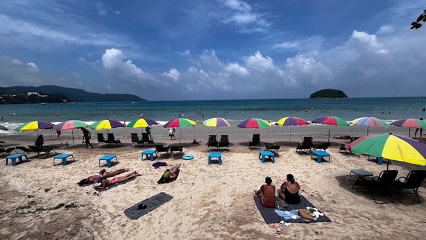 Une plage bordée de rangées de parasols colorés et de chaises de plage.