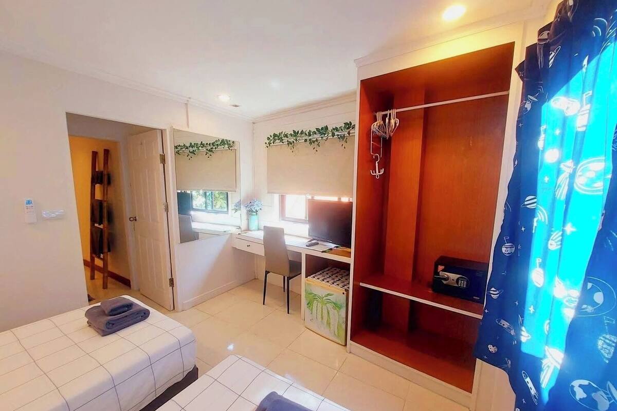 Quarto pequeno com cama, escrivaninha e armário.