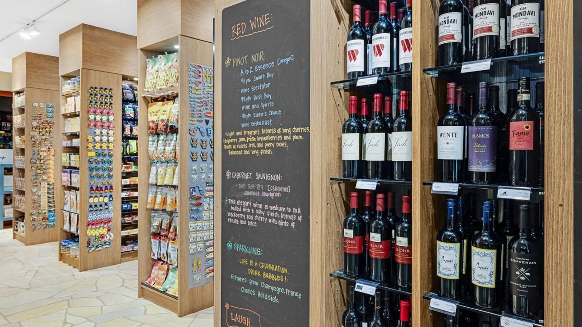 A wine shop with shelves of various wine bottles and a chalkboard menu listing wine types and prices.