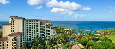 A resort with a large building, a pool area, and a view of the ocean.