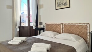Et hotelværelse med en seng, hvide håndklæder, et natbord, en lampe og et billede i ramme på væggen.