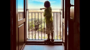 Et barn står på en balkon med udsigt over himlen og landskabet.