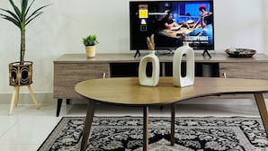 A living room with a TV, a coffee table, a potted plant, and framed artwork on the wall. - CoreSoho Suite by BKAstaycation KotaWarisan Sepang KLIA Airport, Free WiFi (Sepang)